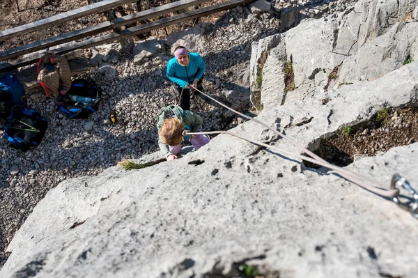 Menina loira bonito escalada usando corda superior com sua mãe protegendo-a. — Fotografia de Stock