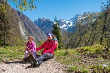 Anne kızını kucaklayarak orman çayırında poz veriyor. Aktif aile açık havada.