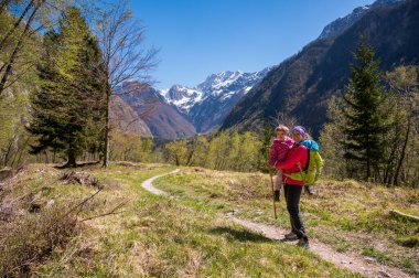 Anne orman çayırında yürürken kızını kucaklıyor. Aktif aile hayatı açık havada.