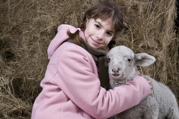 Flicka med ett lamm i närheten — Stockfoto