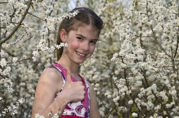 Flicka med vita blommor visar ok skrattar — Stockfoto