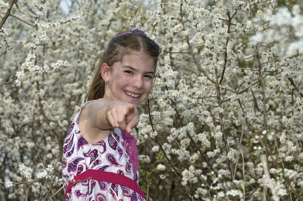 Niña con flores blancas señalando felizmente — Stockfoto