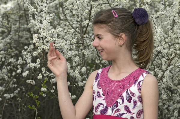 Menina olhando e tocando flores brancas — Fotografia de Stock