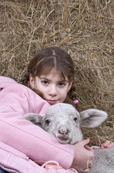 Flicka med lamm i hö — Stockfoto