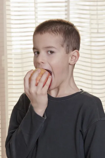 Niño comiendo manzana vista lateral — Foto de Stock