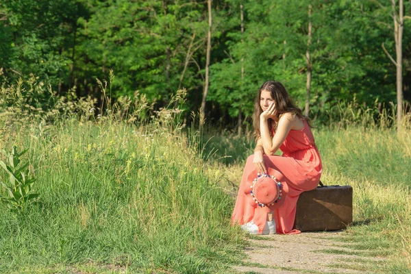 Mladá Žena Červených Šatech Kloboukem Sedí Staré Hnědé Kufr Lese — Stock fotografie