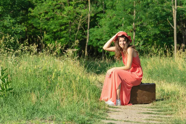 Mladá Žena Červených Šatech Kloboukem Sedí Staré Hnědé Kufr Lese — Stock fotografie