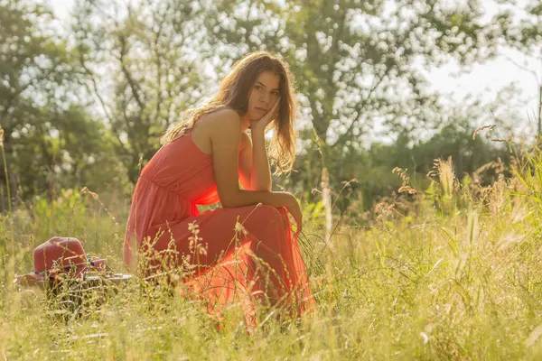 Mladá Žena Červených Šatech Sedí Kufru Dívá Kamery Lese Podsvícením — Stock fotografie