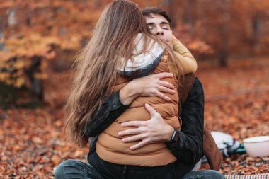Genç, romantik bir çift ormanda sıkıca sarılıyor. Sonbahar zamanı
