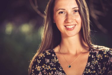 Genç, güzel, esmer bir kızın yaz elbisesi içinde yakın plan portresi.