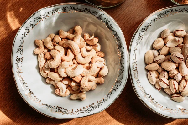 テーブルの上には 磁器の中のカシューナッツとピスタチオ 健康的な軽食 — ストック写真
