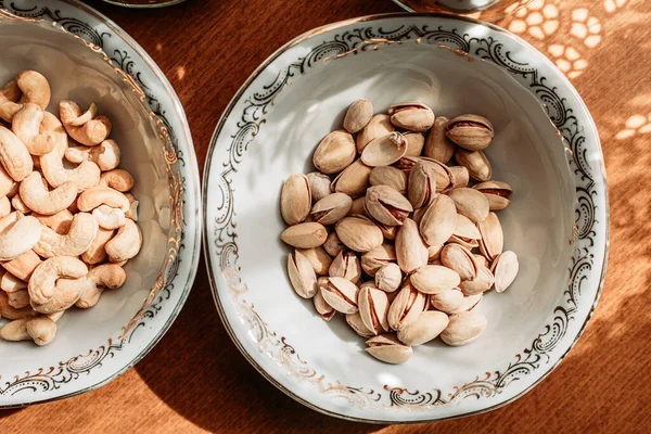 テーブルの上には 磁器の中のカシューナッツとピスタチオ 健康的な軽食 — ストック写真