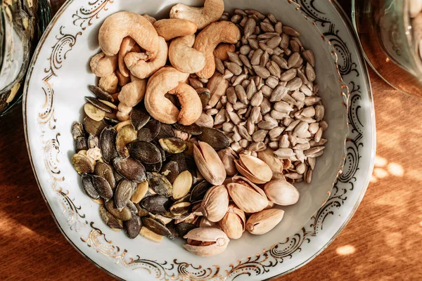 テーブルの上の磁器ボウルには カシューナッツ ピスタチオ ひまわりの種 カボチャの種 健康的な軽食 — ストック写真