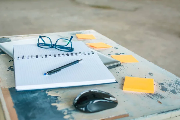 Side view of pen, notebook, pen, laptop, mouse, eyeglasses and reminder stickers on the table. Business, education concept