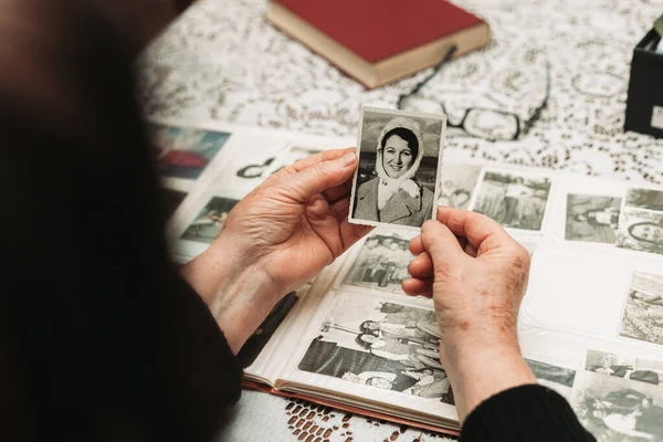 Genç bayanın siyah beyaz fotoğrafını tutan yaşlı kadın elleri. Zaman kavramı geçiyor