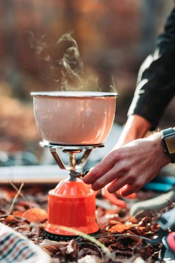 Male hand preparing soup on portable gas stove