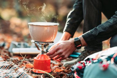 Male hand preparing soup on portable gas stove