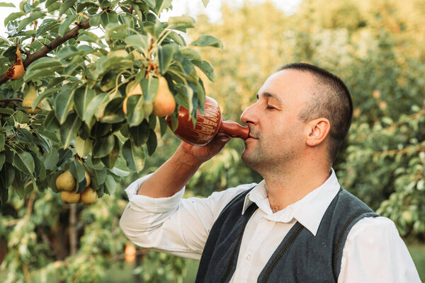 Young man in traditional Serbian clothing drinking from clay pot