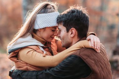 Genç çift ormanda sıkıca sarılıyor.