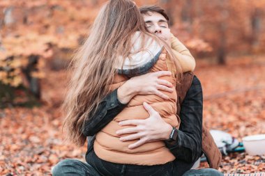 Genç, romantik bir çift ormanda sıkıca sarılıyor. Sonbahar zamanı