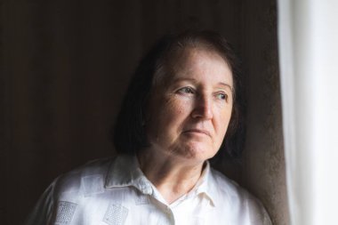 Ayakta duran ve pencereden bakan yaşlı kadın..