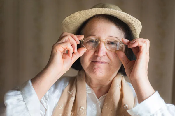 Portrait of an elderly woman putting on her eyeglasses. Vision problems