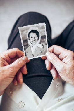 CIRCA 1970: Yaşlı kadın, genç bayanın klasik, siyah beyaz fotoğrafını tutuyor. Zaman kavramı geçiyor
