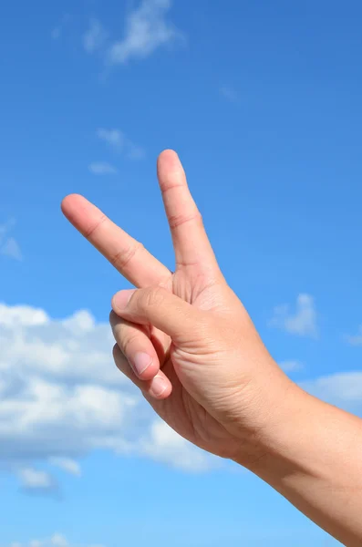 Twee vinger van menselijke hand op blauwe hemelachtergrond — Stockfoto