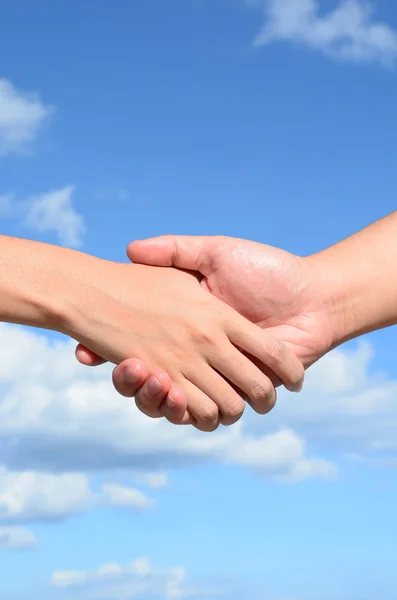 Partner hand tussen een man en een vrouw op blauwe hemelachtergrond, teamwerk Stockfoto