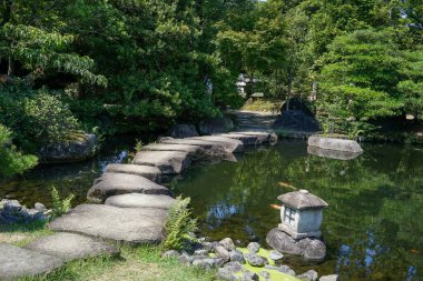 Japonya, Himeji 'de bonsai ağaçları ve balık havuzu olan yeşil bir bahçe..