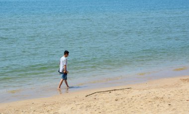 Phan Thiet, Vietnam 'da sahilde yürüyen genç bir Asyalı. Phan Thiet, güneyde birçok lüks tatil köyü olan ünlü bir sahil kentidir..