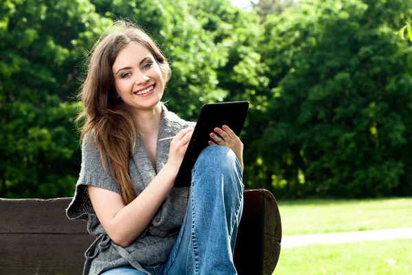 Красивая женщина работает с планшетом в парке — стоковое фото