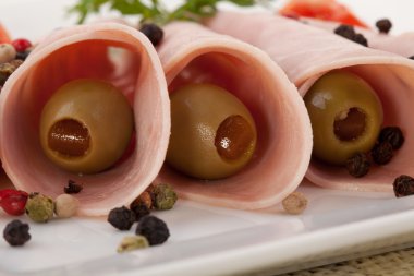 bir tabakta yeşil zeytin ile pişmiş jambon