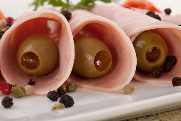 Cooked ham with green olives served on a plate — Stock Photo, Image