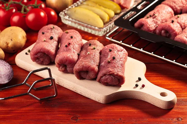 Rollos de carne cruda en una tabla de madera — Foto de Stock