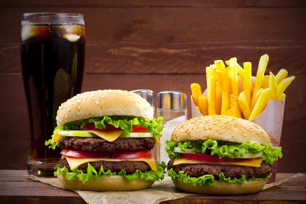 Twee hamburgers met frietjes en cola op hout — Stockfoto