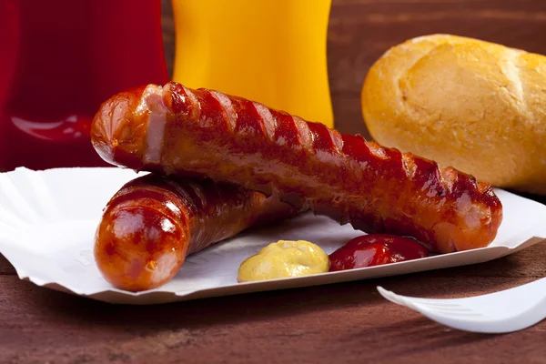 Ristet pølse med brød serveret på en papirbakke - Stock-foto