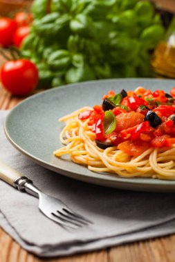 Domates ve zeytinli İtalyan spagetti alla Pultanesca. Et ve peynir olmadan servis edilir. Ön manzara. Doğal ahşap zemin. 