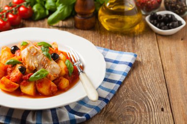 Geleneksel ispanyolca morina balığı. Domates sosunda haşlanmış patates, olivki ve fesleğen ile servis edilmiş. Ön görünüm. 