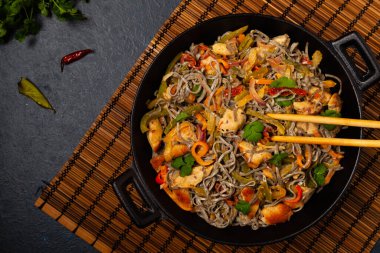 Siyah susamlı buğday eriştesi, tavuk ve sebzeli tavada kızartılmış. Üst görünüm.