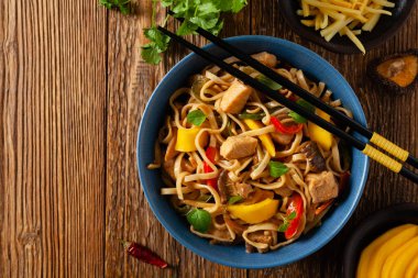 Mangolu kızarmış tavuk ve erişteli hindistan cevizi sütü. Bir tavada hazır. Üst Manzara. Mavi bir kasede servis edildi..