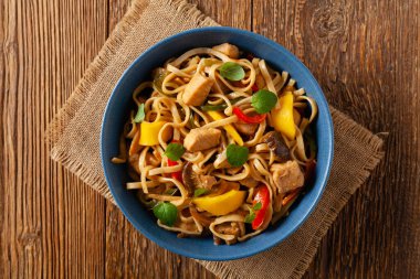 Mangolu kızarmış tavuk ve erişteli hindistan cevizi sütü. Bir tavada hazır. Üst Manzara. Mavi bir kasede servis edildi..