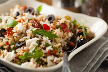 Kırmızı pirinçli moda öğle yemeği, sebze ve sebze karışımı. Ön manzara. Gri ahşap arka planda beyaz kasede servis ediliyor.. 