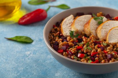 Mısır gevreği, pancar kökü ve tavukla moda bir öğle yemeği. Mavi boyalı arka planda bir kasede servis edilmiş. Ön görünüm. 