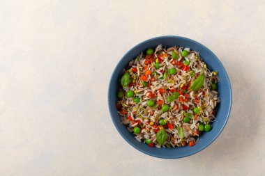 Pirinç ve sebzeli moda öğle yemeği. Mavi bir kasede servis edilmiş, parlak bir arka planda. Üst görünüm.