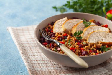 Mısır gevreği, pancar kökü ve tavukla moda bir öğle yemeği. Mavi boyalı arka planda bir kasede servis edilmiş. Ön görünüm. 