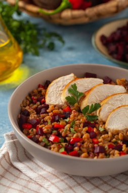 Mısır gevreği, pancar kökü ve tavukla moda bir öğle yemeği. Mavi boyalı arka planda bir kasede servis edilmiş. Ön görünüm. 