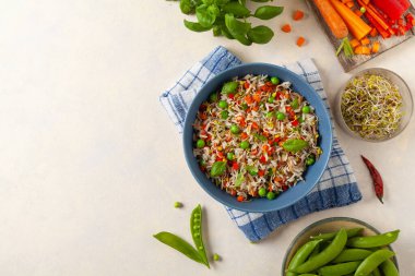 Pirinç ve sebzeli moda öğle yemeği. Mavi bir kasede servis edilmiş, parlak bir arka planda. Üst görünüm.