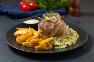 Kaynamış eklem, lahana ve fırında patates ile servis edilir. Ön manzara. Koyu mavi arka plan. Koyu mod. 