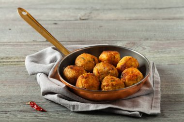 Mercimek ve darı köftesi. Karabuğdaylı domates sosu ile servis edilmiş. Gri plaka, arka planda tahta tahtalar. Ön görünüm.